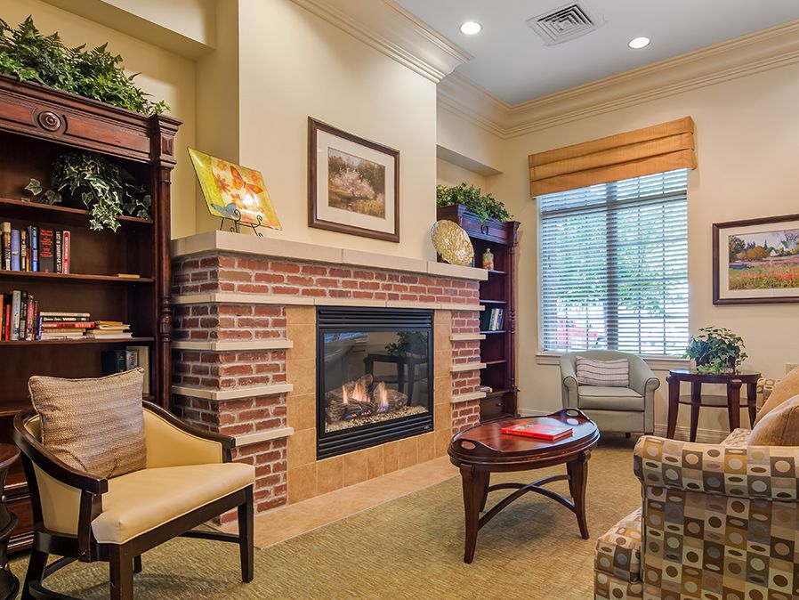 A cozy living room with a brick fireplace, comfortable seating, and bookshelves.