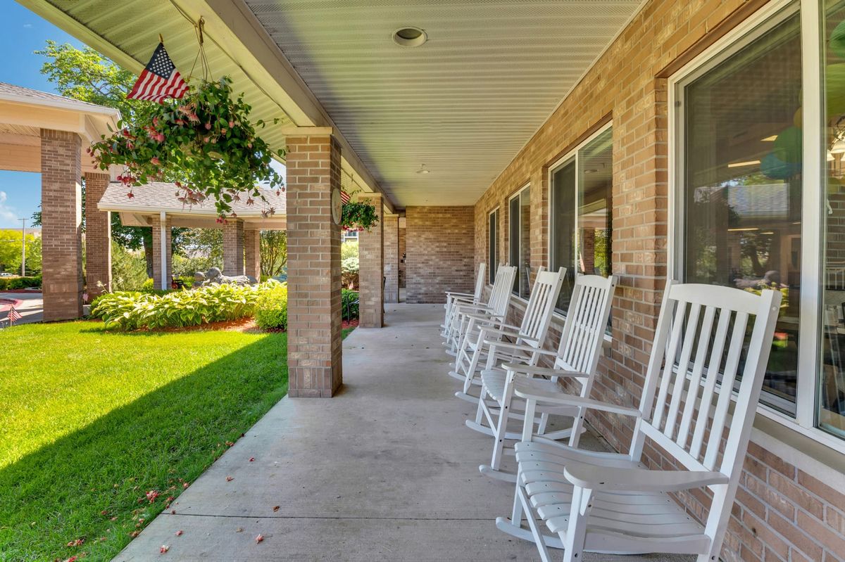 A peaceful porch with white rocking chairs and a garden view.