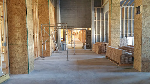An interior view of an ongoing construction site featuring scaffolding and bare walls.