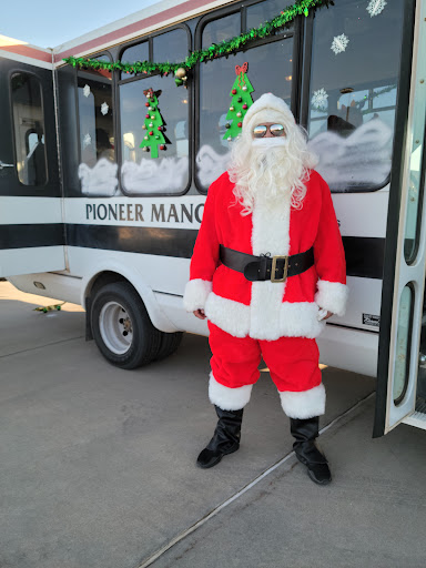 A festive Santa Claus stands by a decorated vehicle, ready to spread holiday cheer.