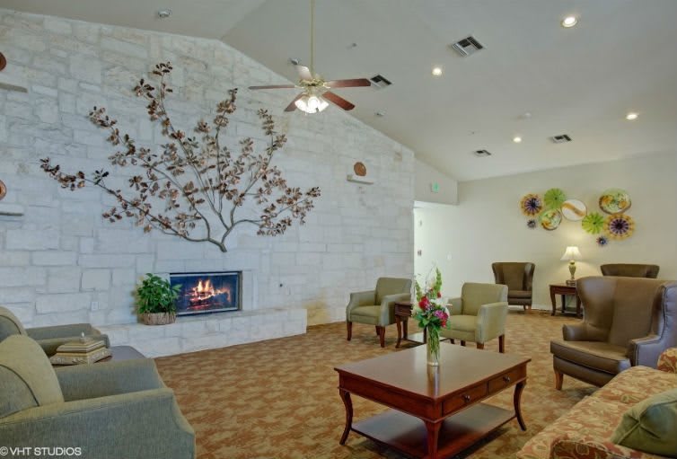 A cozy living room with a fireplace and seating area, featuring decorative wall art.