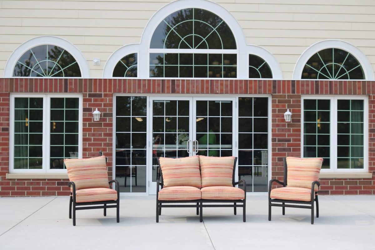 Outdoor patio setting with cushioned chairs and a brick wall backdrop.