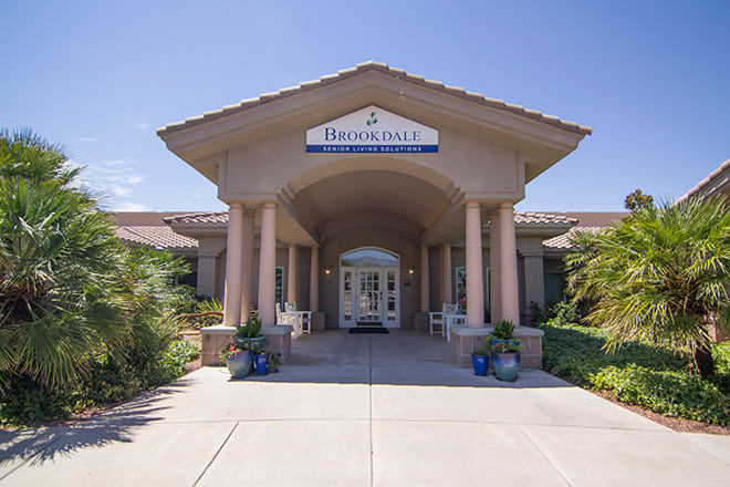 A welcoming entrance to a residential building with columns and landscaping.