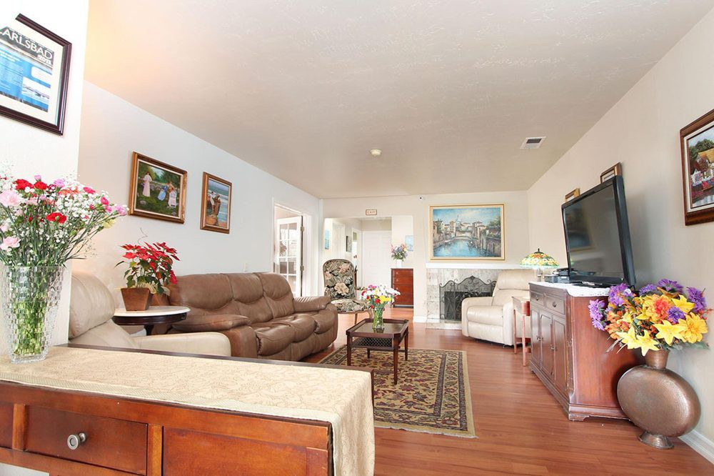 A cozy living room with a sofa, artwork on the walls, a television, and wood flooring.