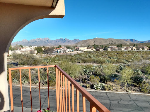 A serene view from the balcony overlooking desert vegetation and distant mountains under a clear blue sky.