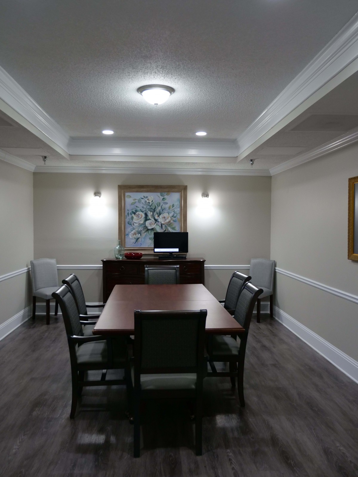 A well-lit conference room with a central table and chairs, decorated with artwork on the wall.