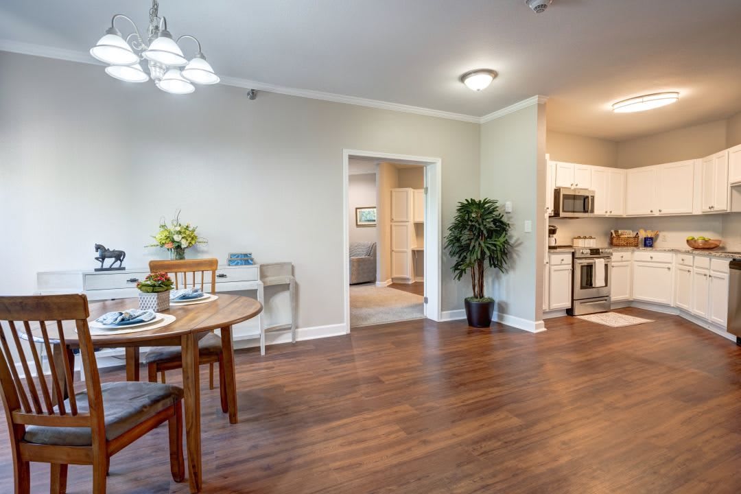 An open-concept dining area next to a modern kitchen with wooden flooring.