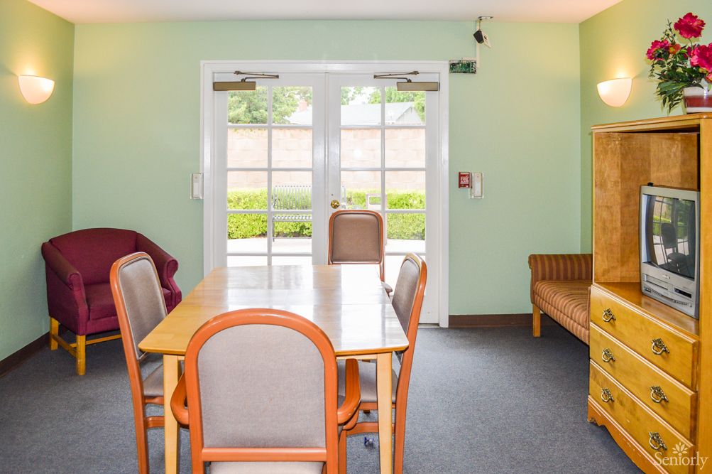 A cozy dining area with a wooden table, chairs, and large windows leading to the outside.