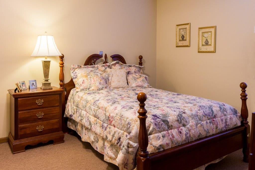 A cozy, traditionally styled bedroom with floral bedding and wooden furniture.