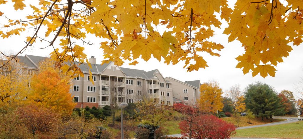 A residential apartment building surrounded by vibrant autumn foliage.