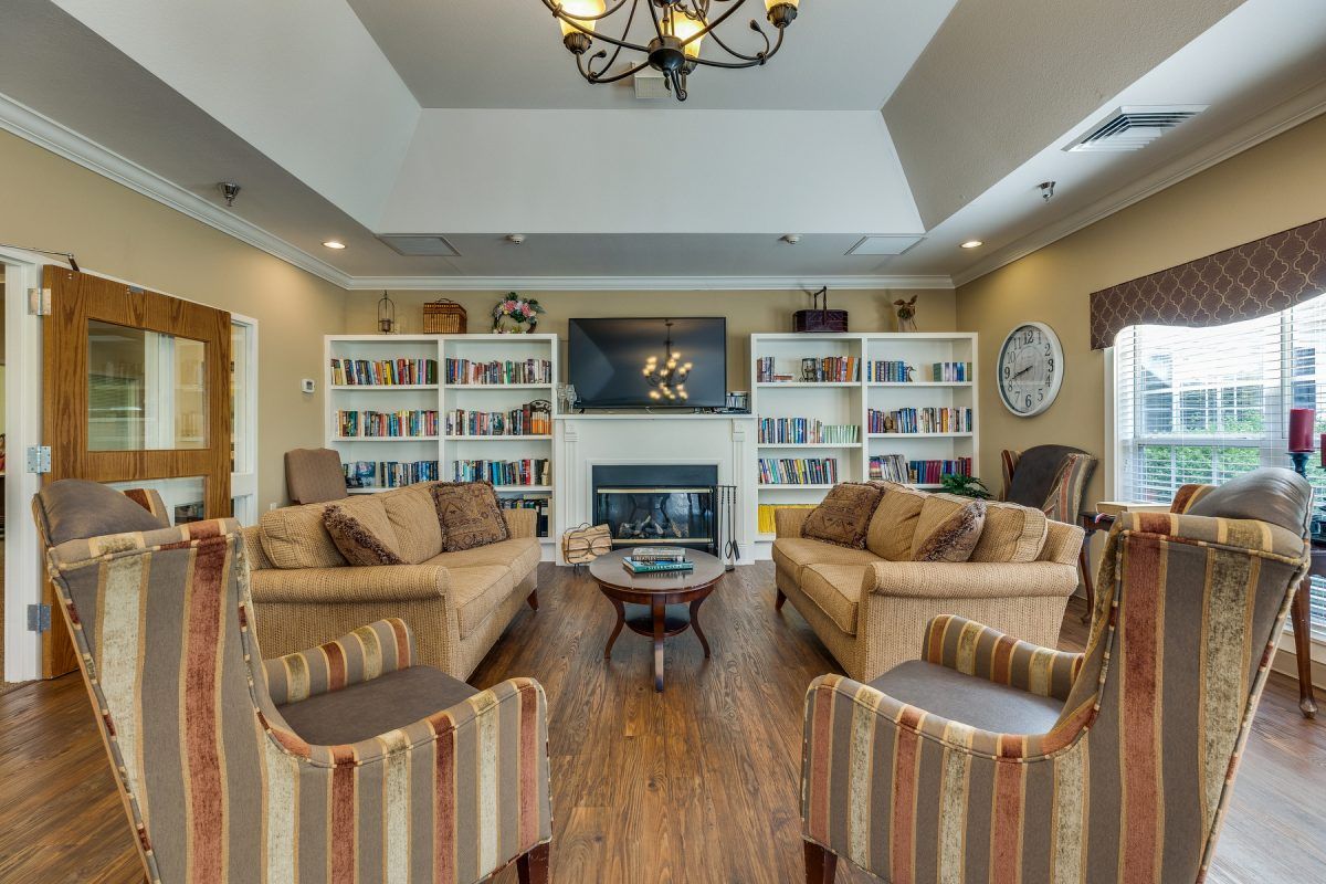 A cozy living room with comfortable sofas, bookshelves filled with books, and a fireplace under a mounted television.