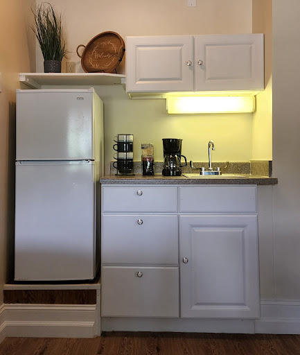 A compact and modern kitchen area featuring essential appliances and white cabinetry.