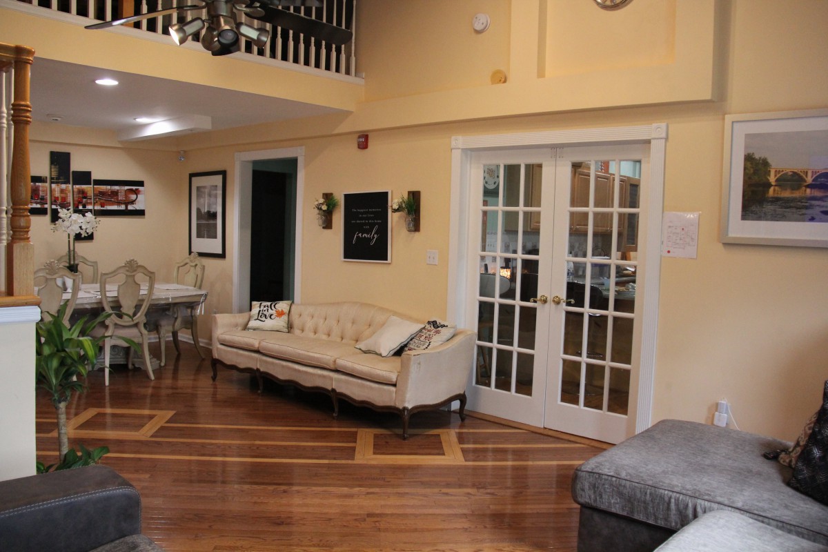 A cozy living room with elegant furniture, including a stylish sofa and a dining table, showcasing hardwood floors and French doors.