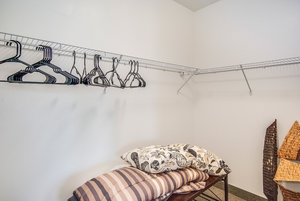 An organized closet with hangers and folded linens on shelves.