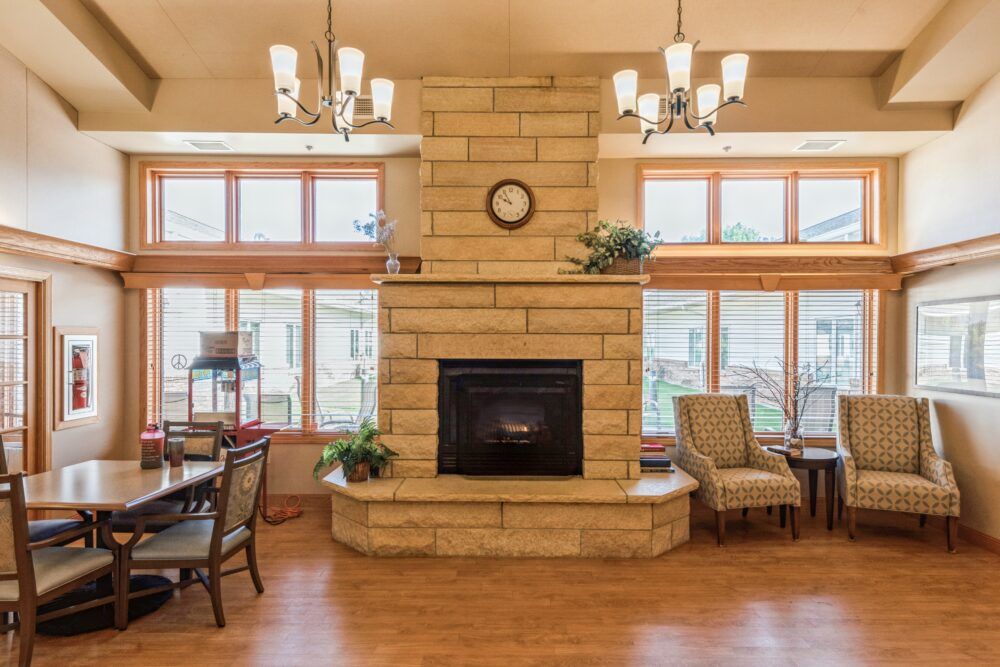 A cozy living room interior featuring a stone fireplace and large windows.