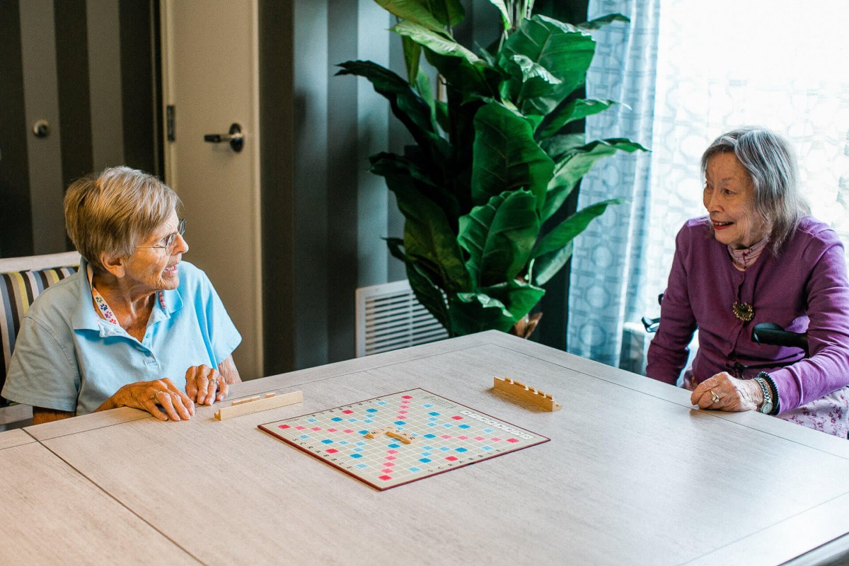 Two senior citizens enjoying a board game together in a cozy indoor setting.