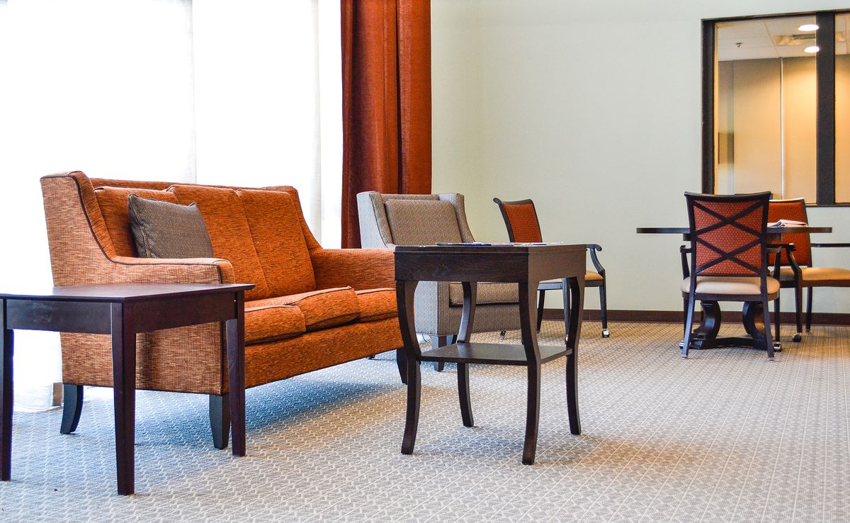 A cozy living room with a comfortable orange sofa, armchairs, and elegant wooden tables.