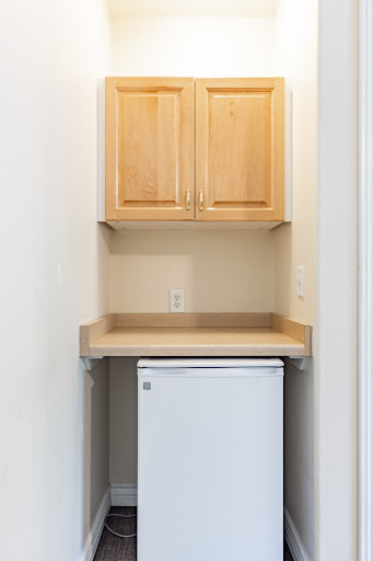 A clean and organized laundry nook featuring cabinets, a countertop, and a mini fridge.