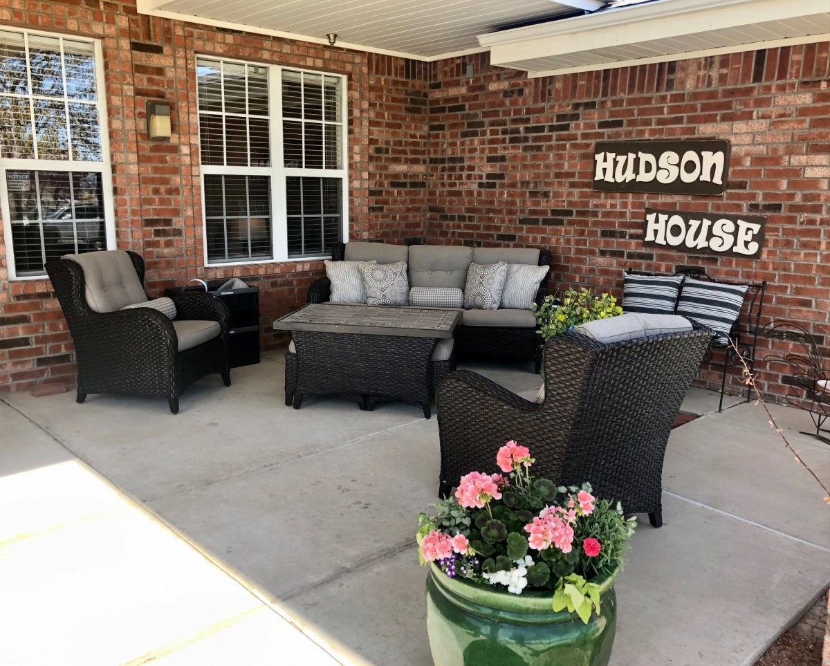 Cozy patio seating area at Hudson House with comfortable furniture and decorative flowers.
