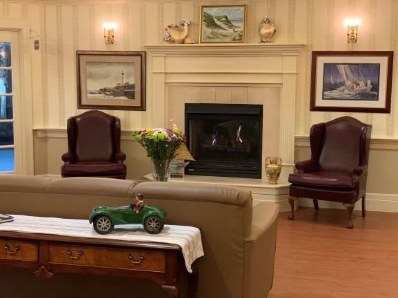 A cozy living room with a fireplace, two armchairs, and decorative items on a table.