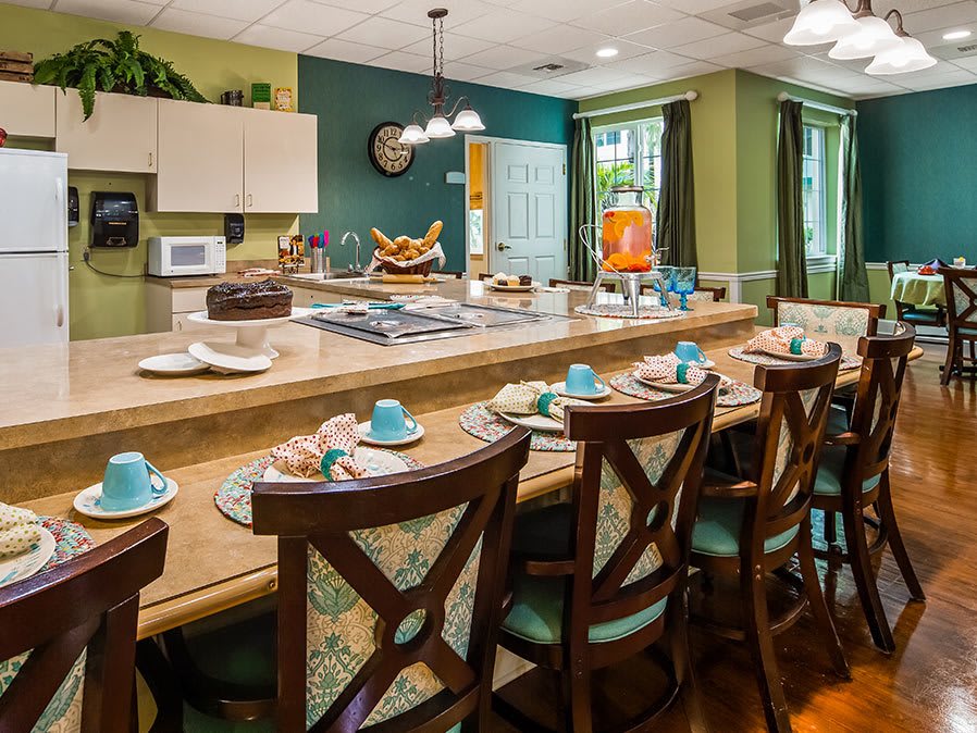 A cozy kitchen and dining area with a bar counter, neatly set with tableware and surrounded by elegant chairs.