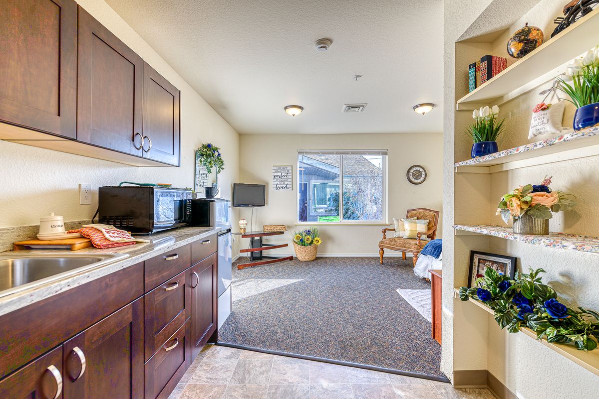 A cozy living space with a kitchenette, featuring a microwave and a window overlooking a garden.