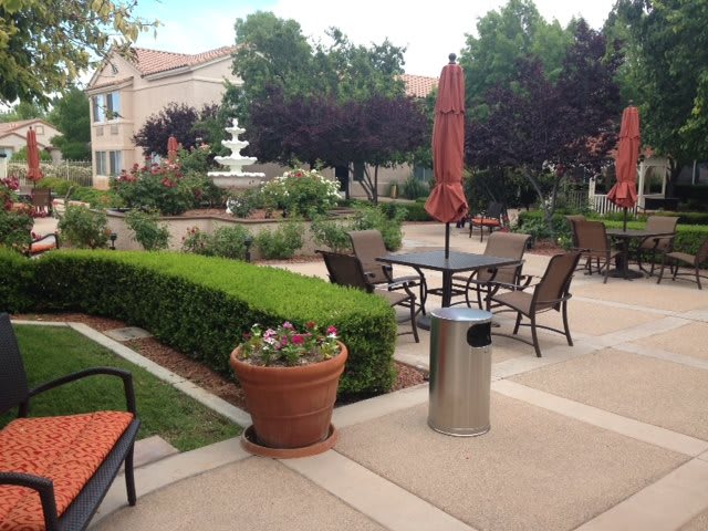 A tranquil outdoor patio with seating and a fountain in a lush garden setting.