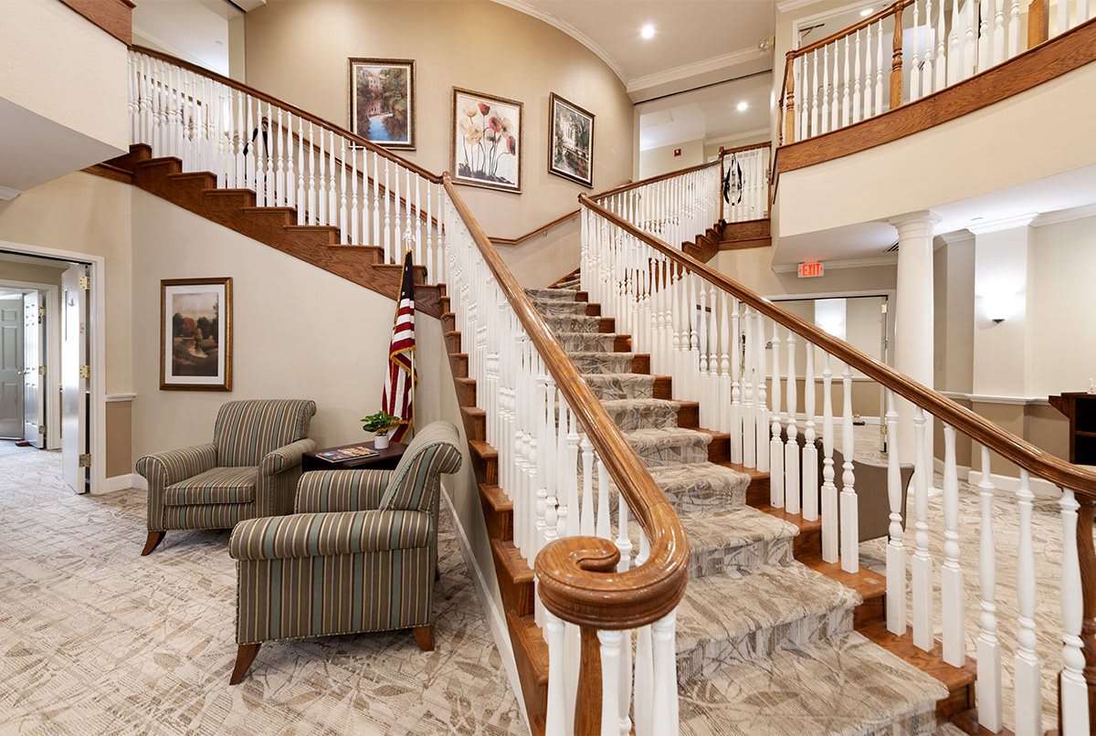 A grand staircase with wooden railings in a lobby featuring seating areas and American-themed decor.