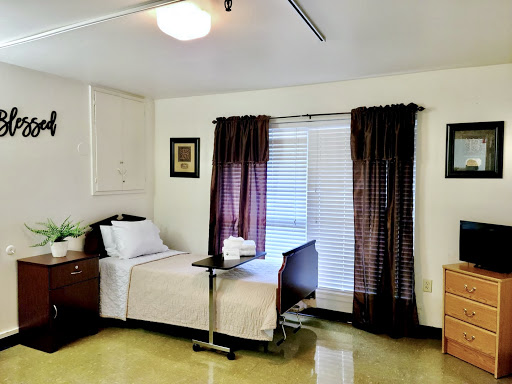 A cozy hospital room featuring a single bed, bedside table, and natural light filtering through the curtains.