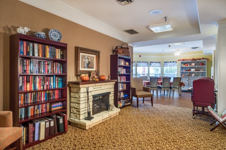 A cozy indoor library with bookshelves, a fireplace, and seating area.
