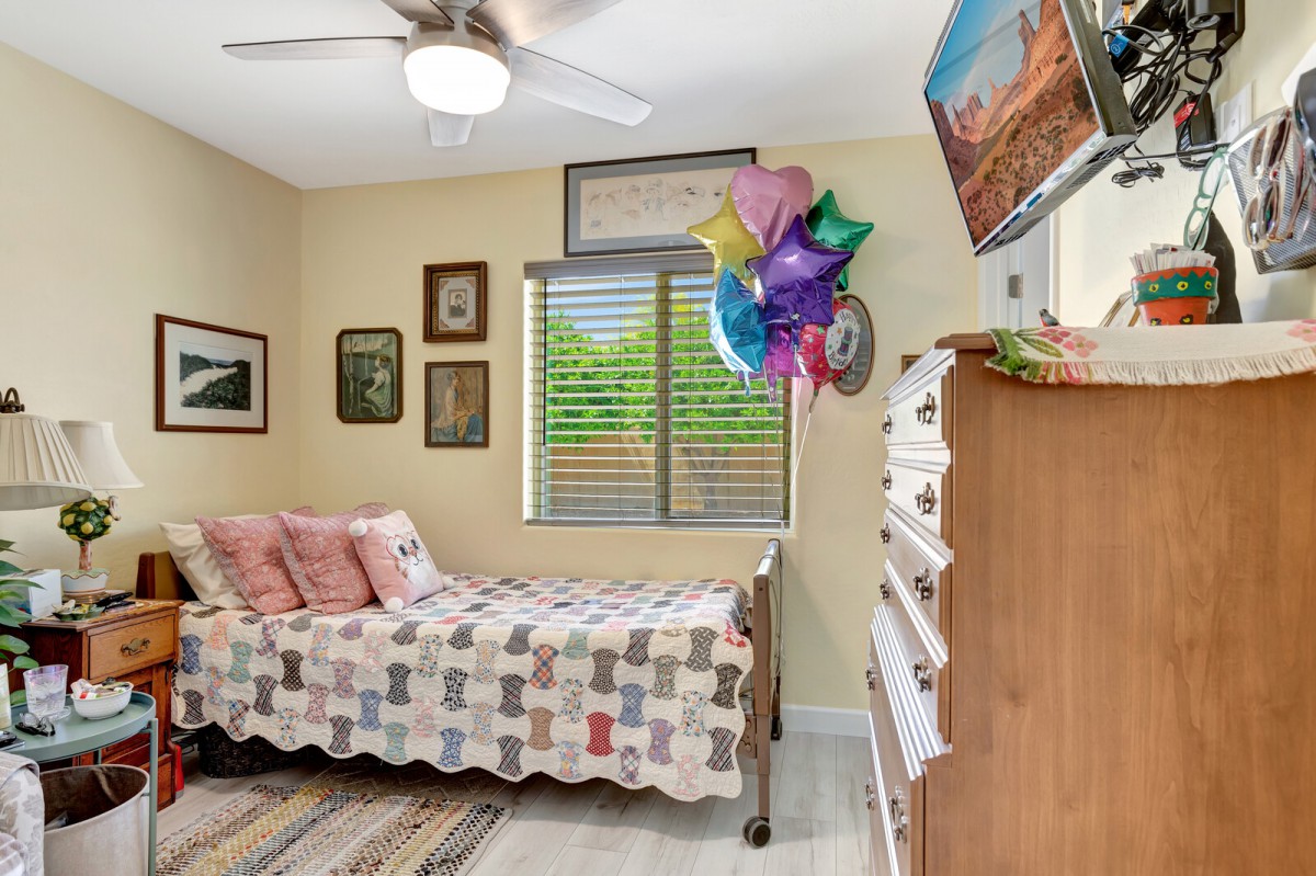 A cozy bedroom with a quilt-covered bed, colorful balloons, and decorative artwork on the walls.