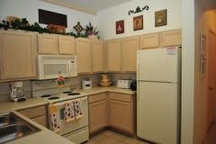 A cozy kitchen with light wood cabinets, featuring a refrigerator, microwave, and oven.