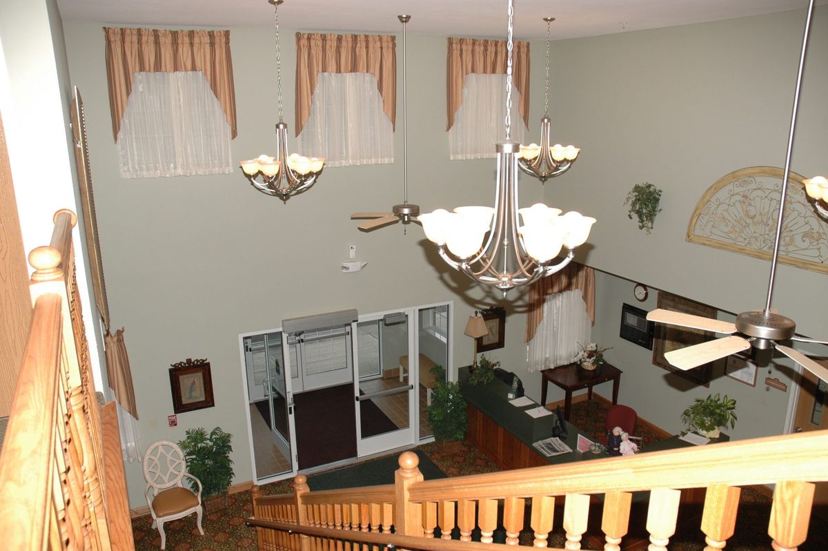 A spacious lobby with chandeliers, a reception desk, and an elegant staircase.