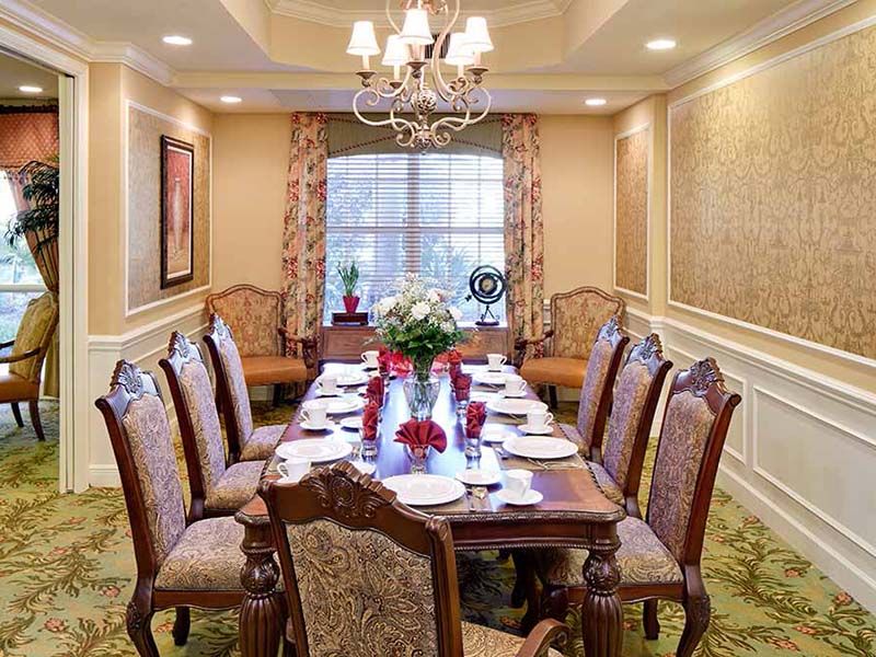 An elegant dining room set for a formal meal, featuring a long table with ornate chairs and a central chandelier.