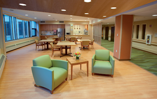 A modern lounge area featuring comfortable green chairs and a wooden table, designed for relaxation and social interaction.