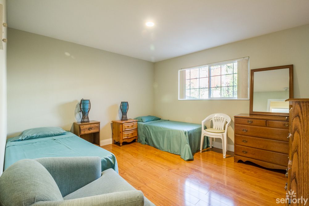 A simple bedroom with two beds and a wooden floor.