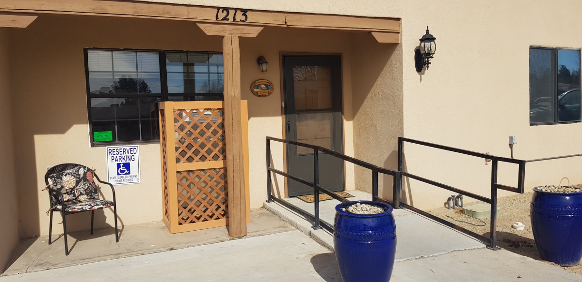Entrance to a building with a blue pot and lattice structure beside the door.