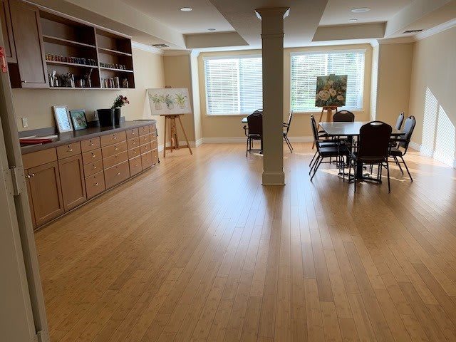 A spacious conference room with wooden flooring and natural light coming through large windows.