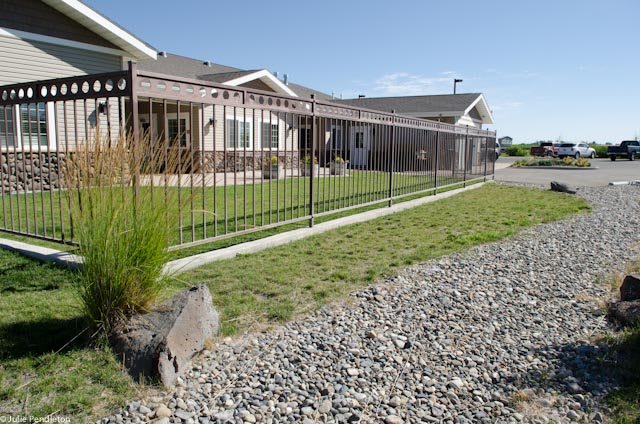 A suburban home with a fenced yard and gravel path.