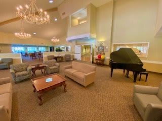 A cozy lounge area featuring comfortable seating, elegant chandeliers, and a grand piano.