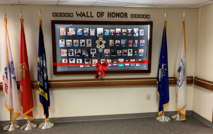 A Wall of Honor display with photographs and flags paying tribute to military personnel.