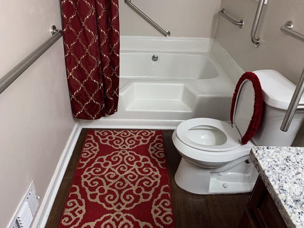 A bathroom featuring a red and white design with a toilet, bathtub, and decorative shower curtain and bath mat.