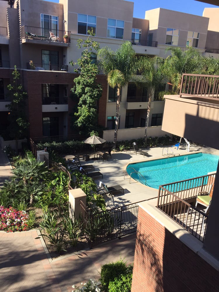 A view of an apartment complex courtyard with a swimming pool and garden.