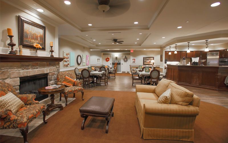 A cozy living room with elegant furniture, including a sofa and dining area, adorned with artwork on the walls.