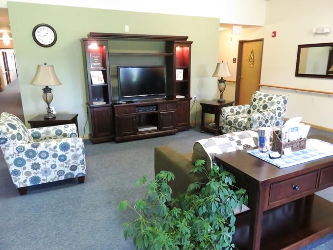 A cozy living room with a TV stand, comfortable seating, and decorative plants.