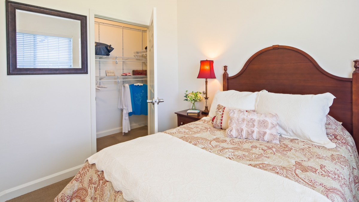 A cozy bedroom with a neatly made bed and an open closet.