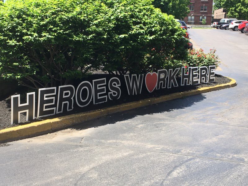 A sign reading 'Heroes Work Here' is displayed outdoors, expressing appreciation for workers.