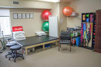 A therapy room equipped with exercise balls, a treatment table, and rehabilitation supplies.