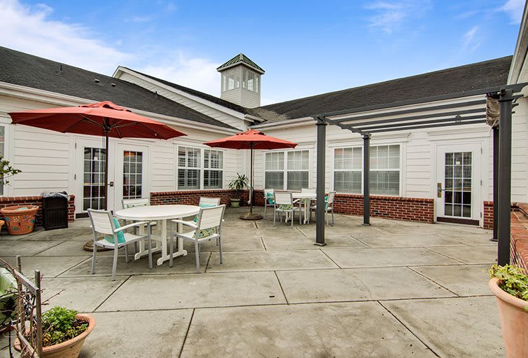 An inviting outdoor patio area with tables, chairs, and umbrellas next to a building.