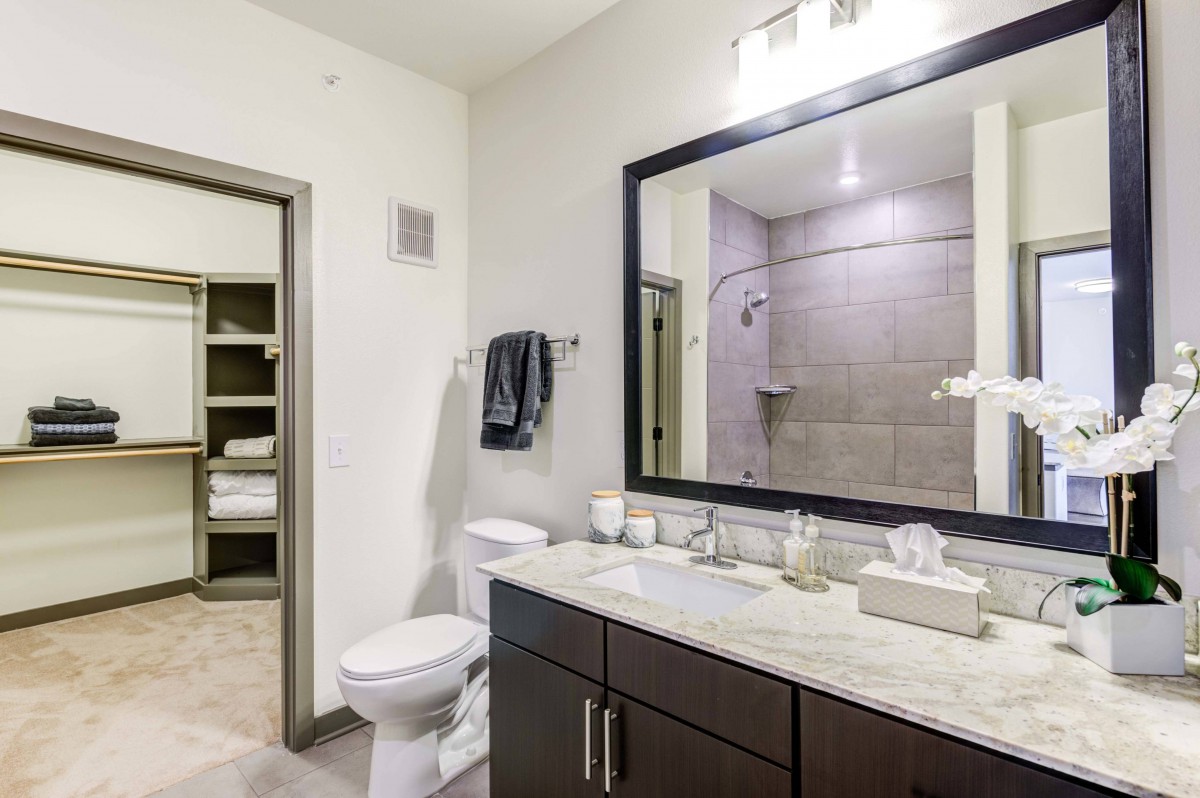 A modern bathroom with a large mirror, vanity sink, and a shower area.